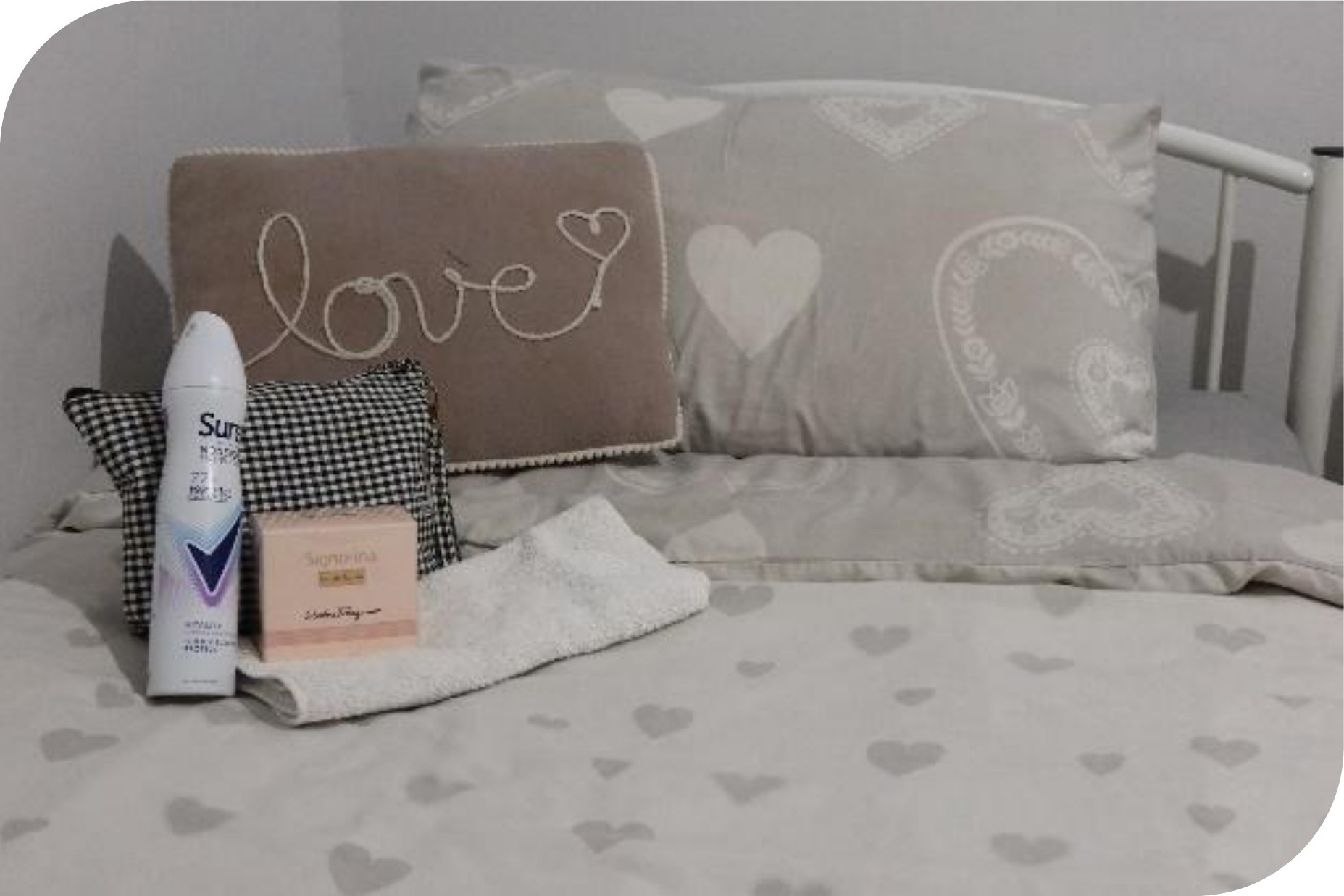 A made bed with a love cushion, towels and welcome essentials