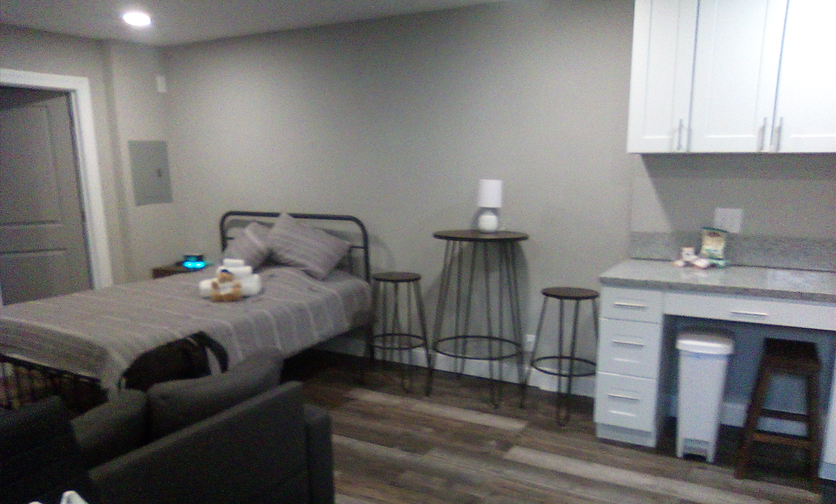 A furnished studio room with a bed, seating and kitchen area